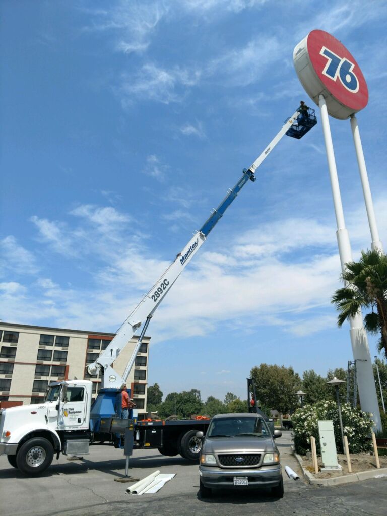 crane with man basket lifting man to repair 76 gas station sign 50 feet in the air