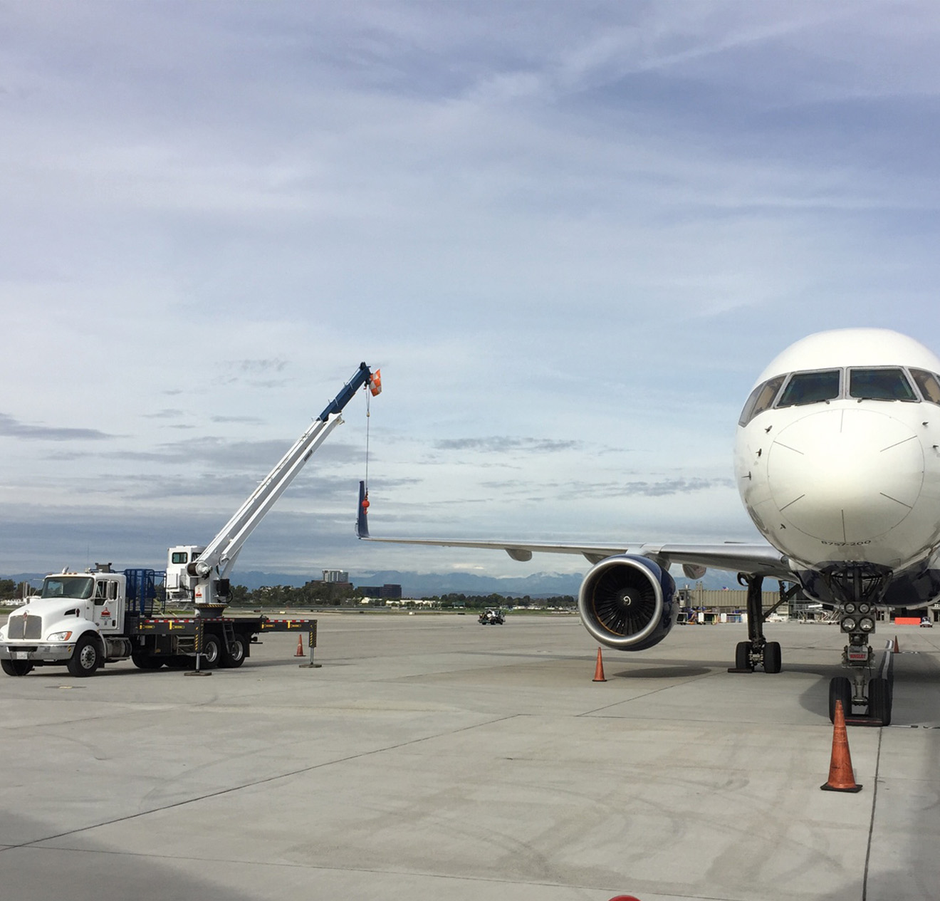 Crane lifting an airplane wing on a tarmac at a commercial airport