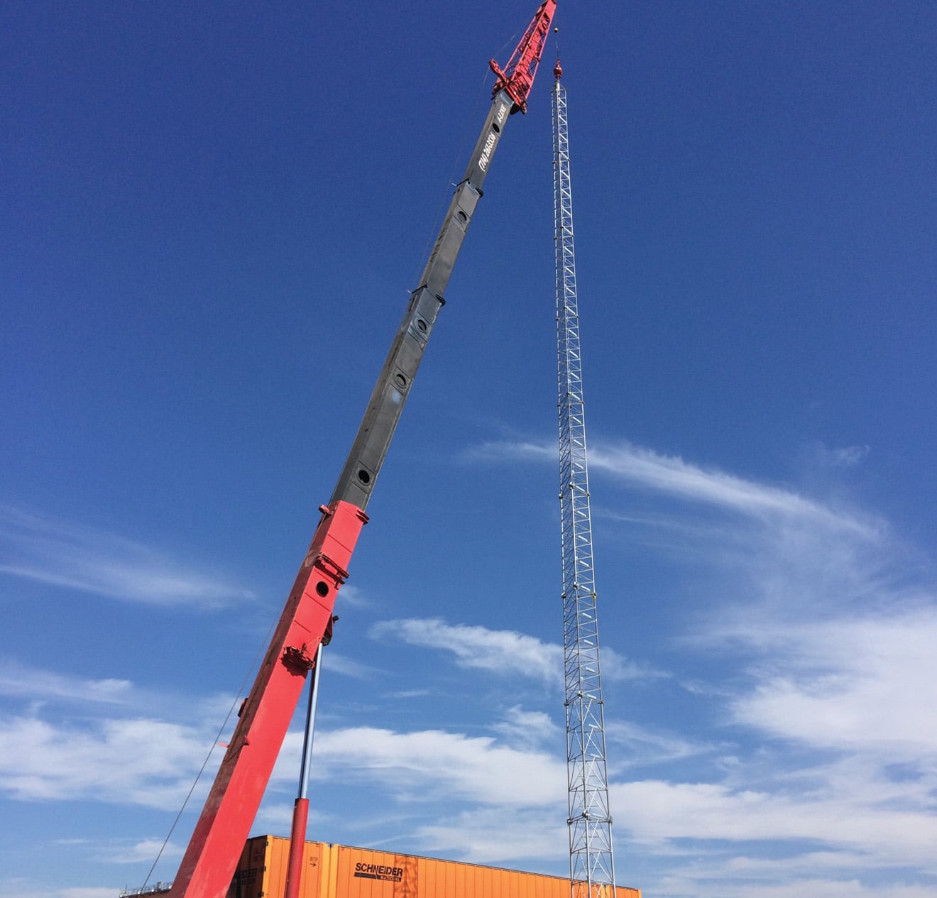 Crane lifting a telephone tower hundreds of feet.