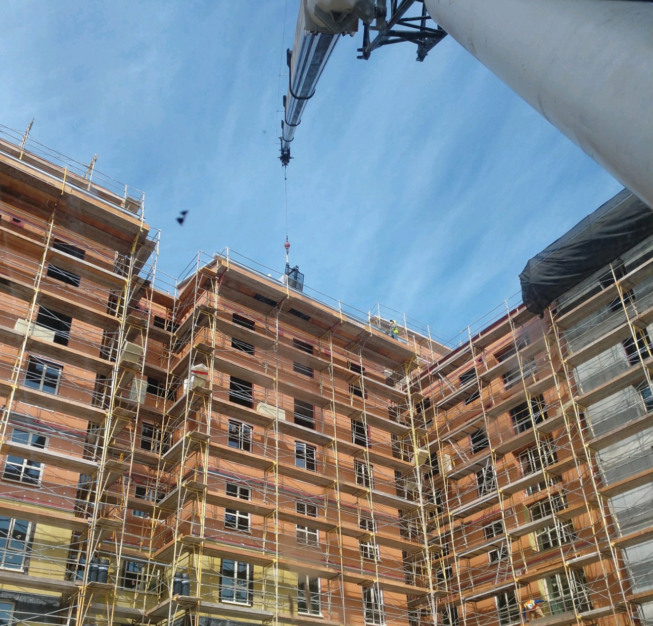 Crane lifting construction materials onto 10 story building.