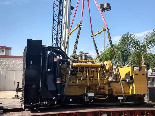 crane lifting heavy machinery onto trailer