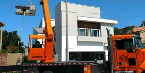 Modular construction crane rental lifts prefabricated unit over builiding