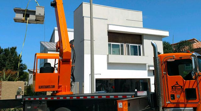 Modular construction crane rental lifts prefabricated unit over builiding