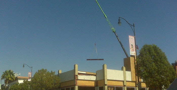 steel erection crane in southern california lifting steel beam onto building